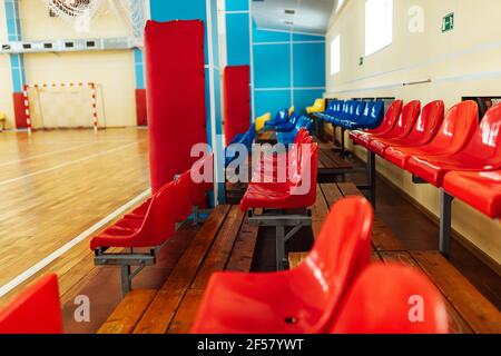 Farbige steht für Fans in einem Hallenstadion. Sitze in der Sporthalle für Wettkämpfe. Leere Bank von Reservespielern Stockfoto