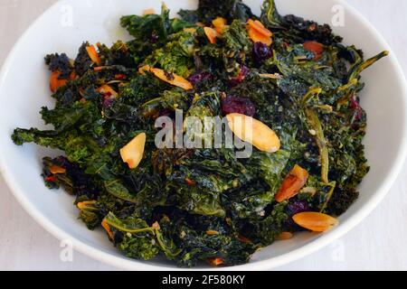 Schüssel gekochten grünen Grünkohl Salat mit getrockneten Preiselbeeren und Mandeln Stockfoto