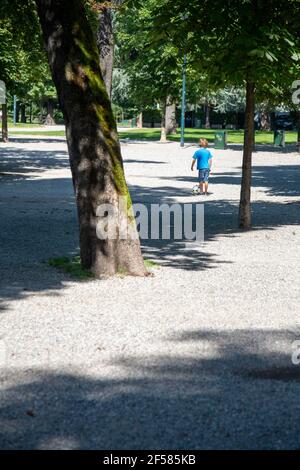 Junger Junge spielt Fußball in EINEM Park allein Stockfoto