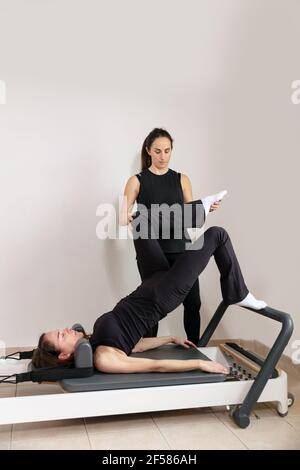 Eine Frau, die Übungen mit einem Pilates Personal Trainer praktiziert. Stockfoto