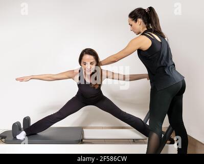 Eine Frau, die Übungen mit einem Pilates Personal Trainer praktiziert. Stockfoto