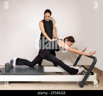 Eine Frau, die Übungen mit einem Pilates Personal Trainer praktiziert. Stockfoto