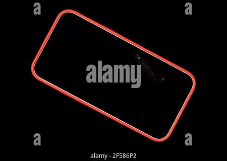 Orangefarbenes Mobiltelefon auf schwarzem Hintergrund Schutzfolie auf dem Telefonbildschirm ist beschädigt, von Stürzen gerissen. Stockfoto