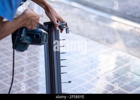Der Techniker verwendet ein elektrisches Gebläse, um Luft zur Reinigung in die Teile der Klimaanlage zu blasen. Stockfoto