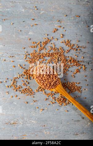 Natürliches Einkorn Bulgur in Holzlöffel auf Holzhintergrund. Draufsicht. Stockfoto