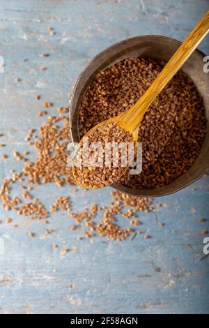 Natürliches Einkorn Bulgur in Holzlöffel auf Holzhintergrund. Draufsicht. (Siyez). Stockfoto