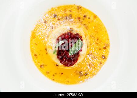 Ingwer-Kürbissuppe mit Knödeln und Beeren. Weißer Hintergrund Stockfoto