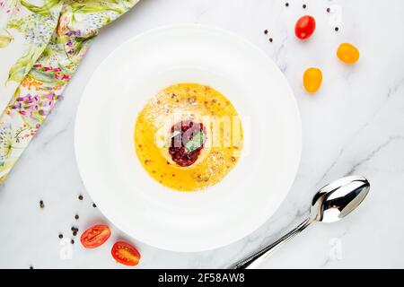 Ingwer-Kürbissuppe mit Knödeln und Beeren. Weißer Hintergrund Stockfoto