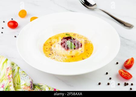 Ingwer-Kürbissuppe mit Knödeln und Beeren. Weißer Hintergrund Stockfoto