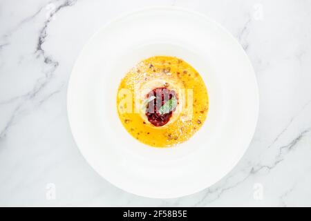 Ingwer-Kürbissuppe mit Knödeln und Beeren. Weißer Hintergrund Stockfoto