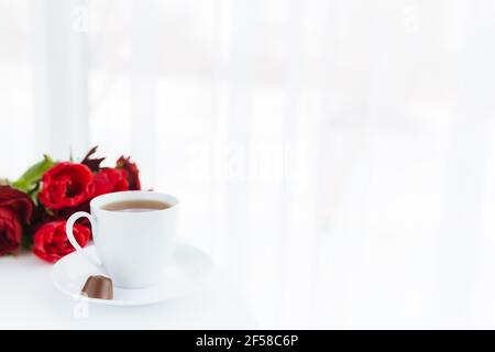 Rote Tulpen Bouquete auf dem Tisch, weiße Kaffeetasse. Konzept für Grußkarte für Muttertag, internationaler Frauentag oder Valentinstag Konzept, birthda Stockfoto