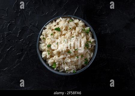 Reis in einer Schüssel, über Kopf auf schwarzem Hintergrund geschossen Stockfoto