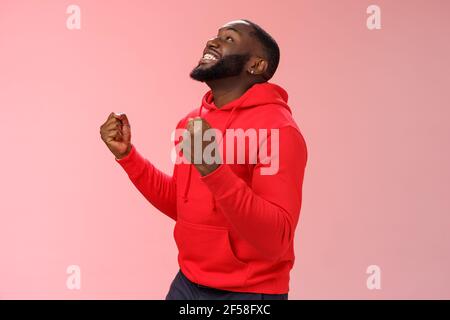 Extrem glücklich aufgeregt jungen afroamerikanischen Mann gewinnen Lotterie Wette Stehend zufrieden Springen freudig triumphierenden Kumpelfäusten feiern Erfolg aussehen Stockfoto