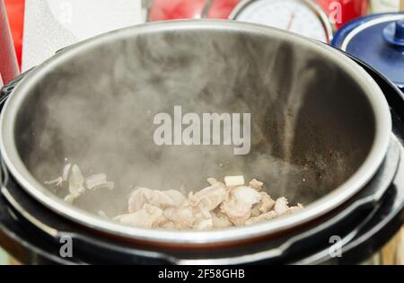 Kochen zu Hause in der Küche nach Rezept aus dem Internet. Kochen von Fleisch im langsamen Herd. Stockfoto