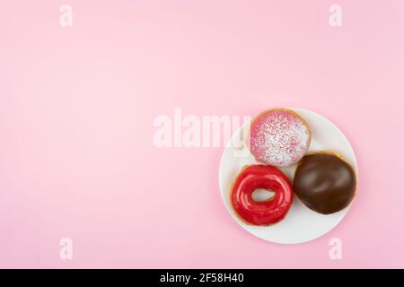 Die leckeren glasierten Donuts liegen auf einem weißen Teller Stockfoto