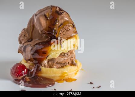 Eis schmelzen auf Waffeln mit Sirup. Schokoladenstreuseln und Kirsche auf weißem Hintergrund mit Kopierraum - leckere Schokolade Eis Wüste Stockfoto