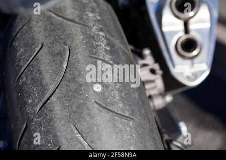 Schrauben Nagel durchstechen Motorrad-Reifen. Nahaufnahme am Hinterrad Stockfoto