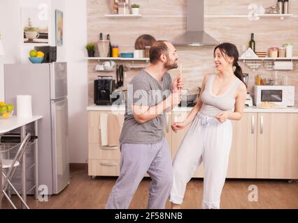 Sorglos glücklich und fröhlich Paar tanzen und singen in der Küche in synny Morgen. Fröhlicher Mann und Frau lachen, singen, tanzen hören, lachen, leben glücklich und sorgenfrei. Positive Menschen Stockfoto