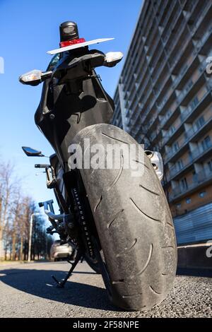 Motorrad steht auf Stand auf der städtischen Straße. Stadt am Straßenrand, niemand, Weitwinkel Rückansicht Stockfoto