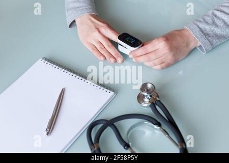 Weibliche Patientenhand zur Messung der Sauerstoffsättigung und des Pulses mit einem tragbaren Oximeter. Gesundheitskonzept Stockfoto