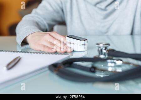 Weibliche Patientenhand zur Messung der Sauerstoffsättigung und des Pulses mit einem tragbaren Oximeter. Gesundheitskonzept Stockfoto