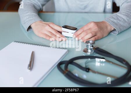 Weibliche Patientenhand zur Messung der Sauerstoffsättigung und des Pulses mit einem tragbaren Oximeter. Gesundheitskonzept Stockfoto