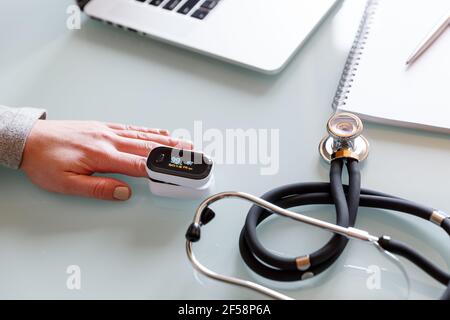 Weibliche Patientenhand zur Messung der Sauerstoffsättigung und des Pulses mit einem tragbaren Oximeter. Gesundheitskonzept Stockfoto