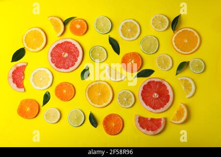 Reife Zitrusscheiben und Blätter auf gelbem Hintergrund Stockfoto