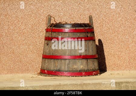 Vintage Retro alten großen Holzweinfass mit rotem Metall Reifen in dekorative Blumentopf mit trockenen Pflanzen gefüllt umgewandelt Stockfoto