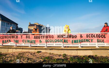 Beaumaris, Anglesey, Nordwales, Großbritannien. 24th. März 2021. Mitglieder der Extinction Rebellion North Wales hängen ein Banner, das die Unterstützung des Klima- und ökologischen Nothilfegesetzes fordert und die lokale Abgeordnete Virginia Crosby auffordert, den Gesetzentwurf zu unterstützen. Stockfoto