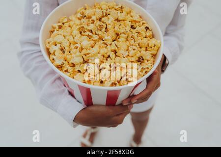 Nahaufnahme eines jungen süßen Mädchens, das eine Tube Popcorn in den Händen hält. Stockfoto