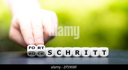 Hand dreht Würfel und ändert das deutsche Wort 'Rückschritt' in 'Fortschritt'. Stockfoto