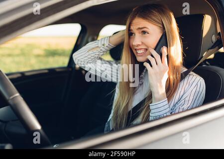 Nahaufnahme Porträt einer lächelnden jungen Frau im Auto sitzen Telefonieren während der Fahrt Stockfoto