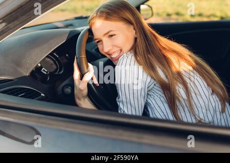 Junge glückliche Frau kauft ein Auto, Dame in einem Auto Salon, elegante jubelende Frau Stockfoto