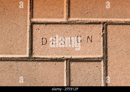 Das Wort Design in die Oberfläche der Ziegelsteinpflaster gestempelt Ein Gebäude- und Baukonzept Stockfoto