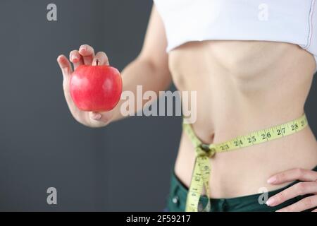 Frau mit Maßband an der Taille hält Apfel in den Händen Nahaufnahme Stockfoto