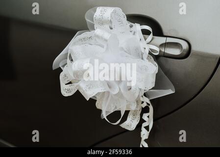 Weiße Schleife am Griff eines Autos - Hochzeit Autodekoration Stockfoto
