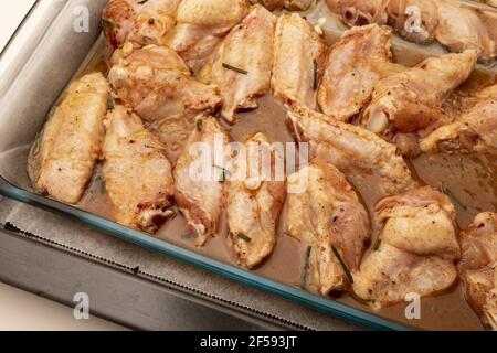 Rohe Hähnchenflügel mariniert mit Öl, Pfeffer, Schnittlauch, Honig und Gewürzen auf einem Backblech Stockfoto