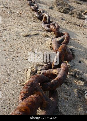 Verrostete Kettenglieder an einem Sandstrand, der am Strand entlang läuft Mittelansicht Stockfoto