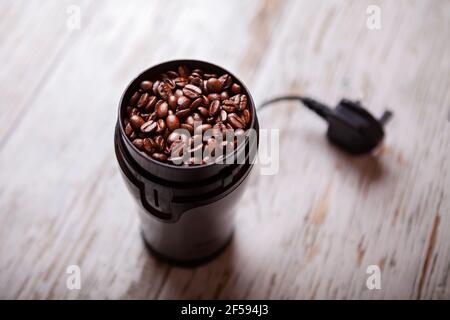 Kaffeebohnen in einer Kaffeemühle auf einem weißen Holz Boden Stockfoto