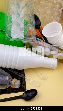 Abfallsortierung. Kunststoffabfälle für das Recycling. Flaschen, Behälter, Gabeln, Löffel, Eierverpackungen, Deckel. Gelber Hintergrund. Umweltfreundlich - kein Abfall. Zero Waste ist ein Trend. Stockfoto