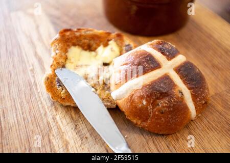 Traditionelles Hot Cross Bun mit geschmolzener Butter ein traditionelles für Ostern Großbritannien - EIN heißes Cross Bun ist ein gewürztes süßes Bun in der Regel mit Früchten, gekennzeichnet mit einem Kreuz auf der Oberseite, und traditionell am Karfreitag in Großbritannien gegessen Stockfoto