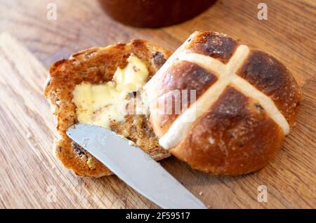 Traditionelles Hot Cross Bun mit geschmolzener Butter ein traditionelles für Ostern Großbritannien - EIN heißes Cross Bun ist ein gewürztes süßes Bun in der Regel mit Früchten, gekennzeichnet mit einem Kreuz auf der Oberseite, und traditionell am Karfreitag in Großbritannien gegessen Stockfoto