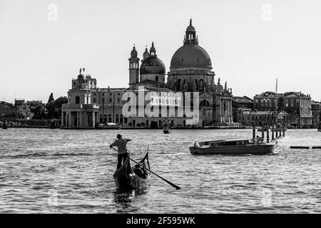 Venedig, Italien - Juni 22 2020: Eine klassische Schwarz-Weiß-Ansicht einer traditionellen Gondel, die auf dem Canal Grande von Venedig mit der Basilica di Santa fährt Stockfoto