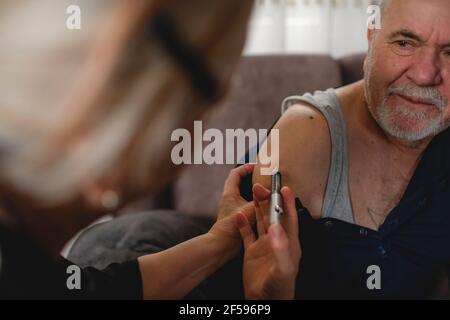 Ältere Frau, die ihrem diabetischen Mann zu Hause Insulin gibt Stockfoto