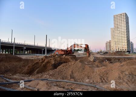 Bagger während der Aushubarbeiten auf der Baustelle. Bagger auf der Straße arbeiten. Maschinen für schwere Baumaschinen für Erdarbeiten. Bagger an der Brückenkonstruktion Stockfoto