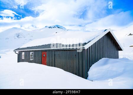 Hütte in den Bergen bedeckt mit tiefem Schnee an einem klaren kalten Wintertag. Stockfoto