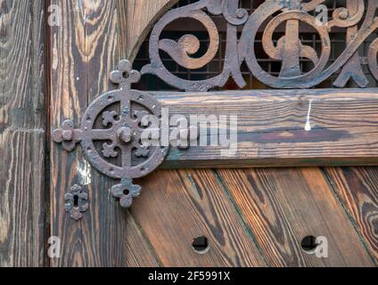 Kunstvolle Eisenarbeiten an einer braunen Holztür in Nahaufnahme. Stockfoto