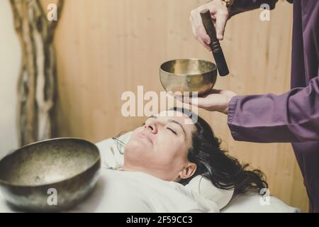 Sanfte Sicht auf eine Frau, die mit tibetischen Glocken ganzheitliche Aktivitäten praktiziert. Meditation und Achtsamkeitsübungen für Ruhe und Klarheit Ihres Geistes. Gut Stockfoto