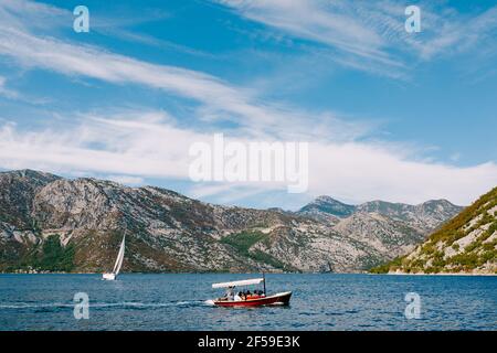 Ein Vergnügen rotes Motorboot mit einer Markise von der Sonne segelt mit Menschen vor der Küste der Stadt. Stockfoto